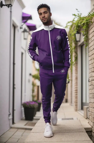 Stylish man walks confidently in a purple Synergetic Heroes tracksuit with bold branding. This premium athleisure set is perfect for workouts, streetwear, and active lifestyles. Elevate your look with Synergetic Heroes apparel—shop now!