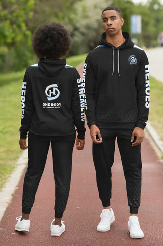 Man and woman wearing matching black Synergetic Heroes hoodies and joggers. Stylish, comfortable athleisurewear for fitness and casual outings.